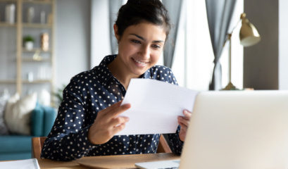 Smiling Indian Woman Holding Reading Paper Letter Sit At Table